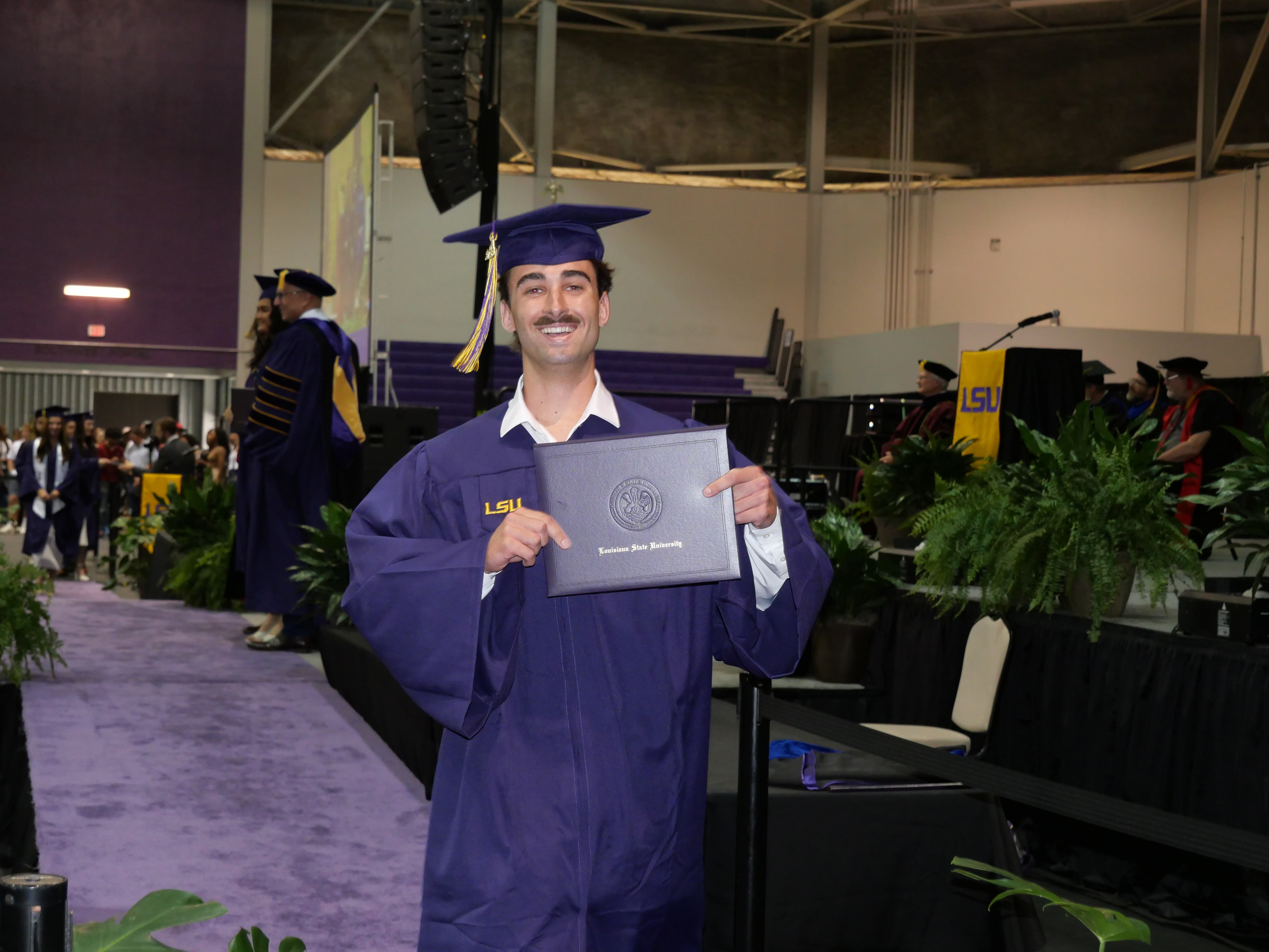 Graduate walking off stage with diploma.