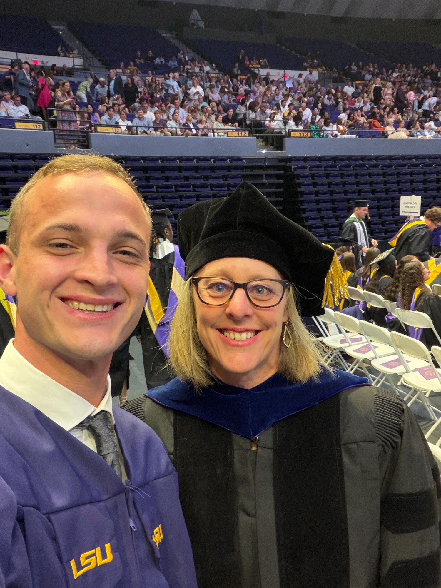 LSU graduate Joshua Smith poses with a faculty member during LSU commencement ceremonies.