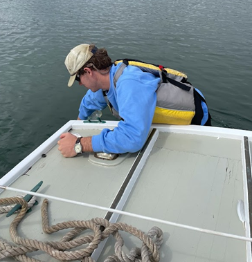 Philip Brahana collects water samples from boat