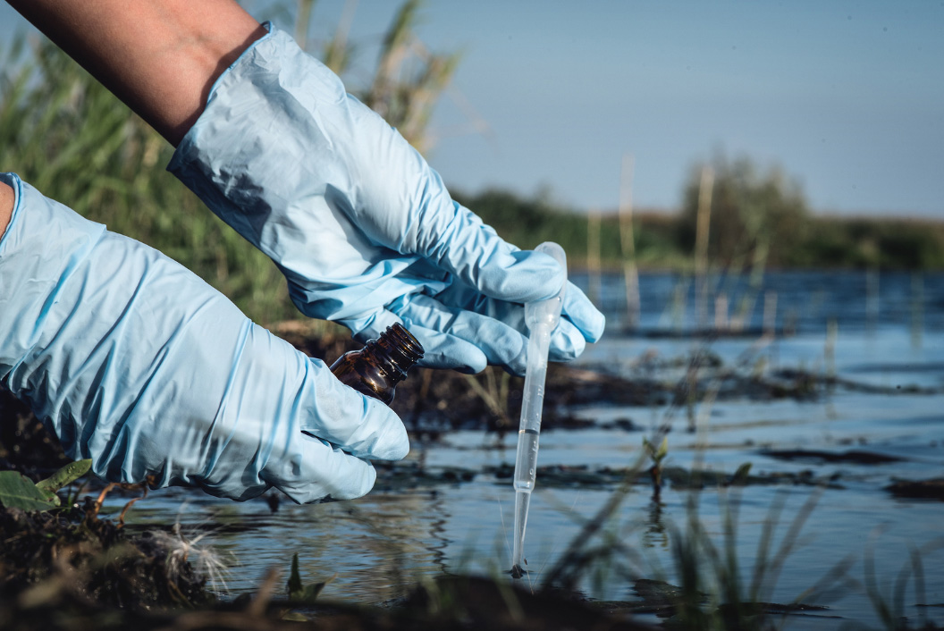 Hands in latex gloves collect a water sample 