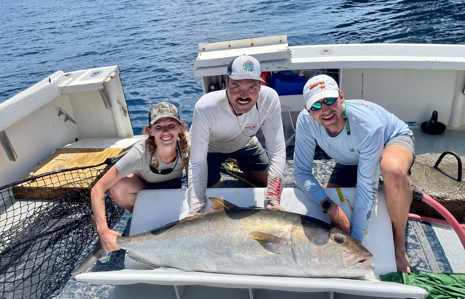 three scientists pose behind a fish 