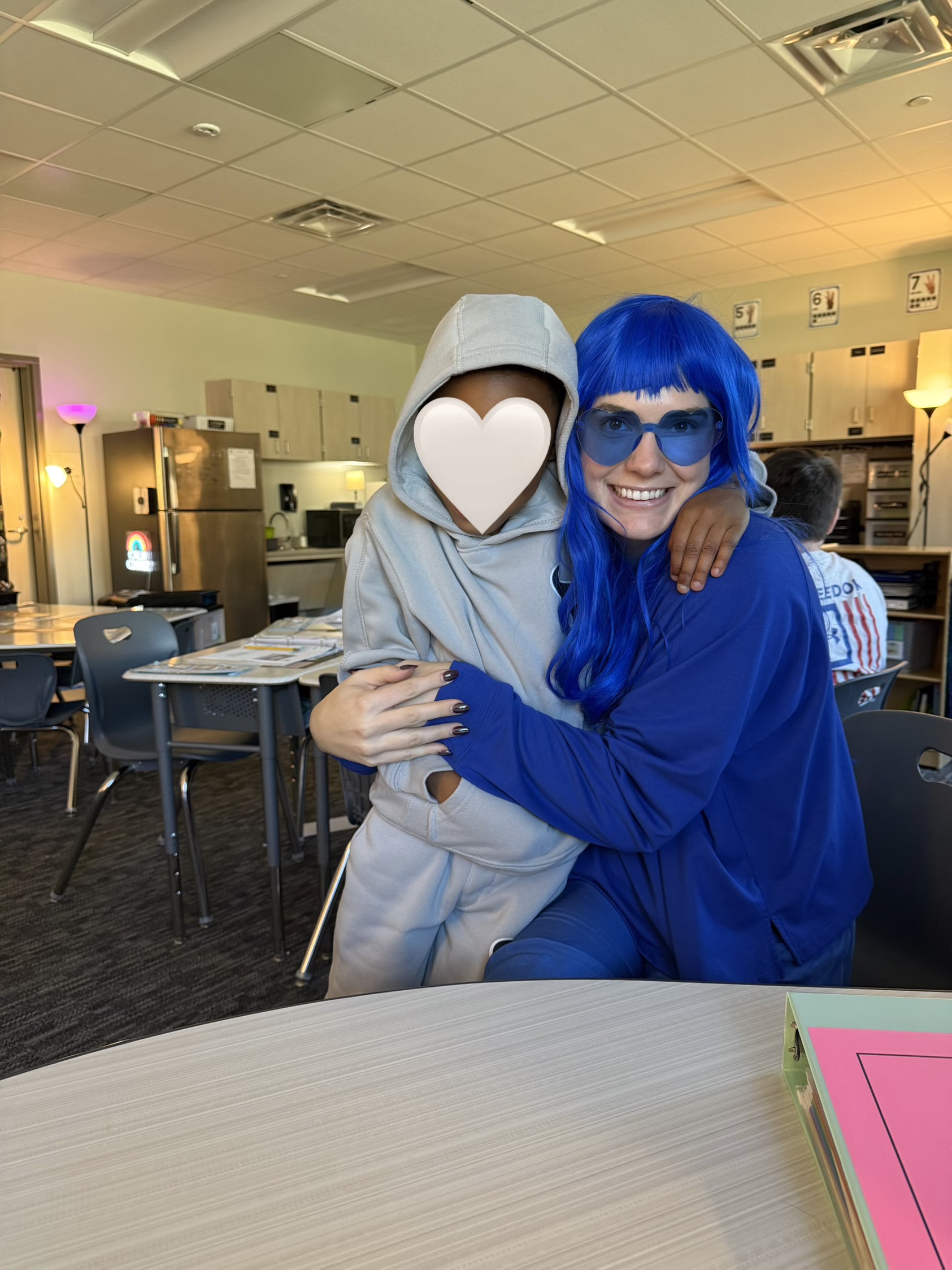 Kaleigh Stallings wearing a blue wig sitting next to a student