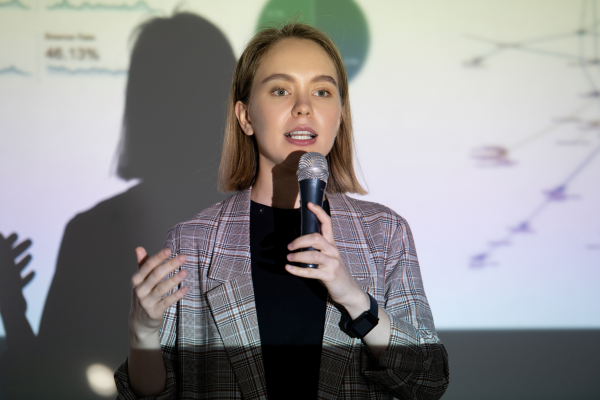 student with a microphone standing in front of a presentation