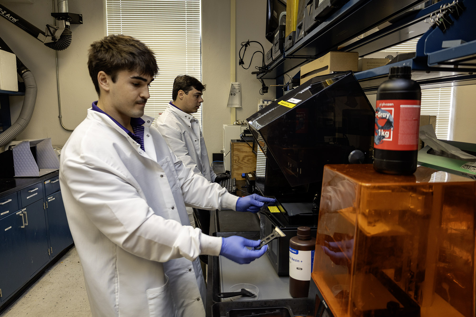 Gerard Lorio and Brennan Comeaux work on lab equipment