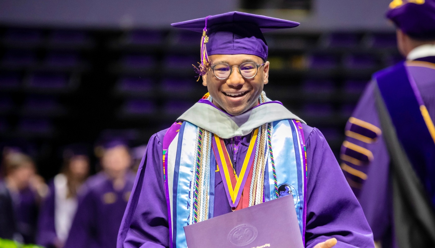 Photo of an LSU Ogden Honors College graduate crossing the stage at commencement