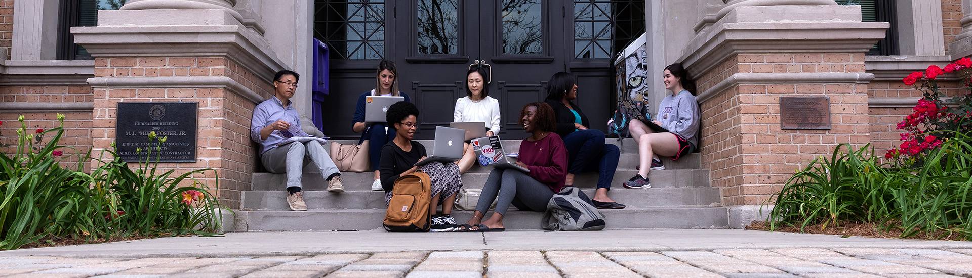 Professors and students on computers outside of the Journalism building Professors and students on computers outside of the Journalism building